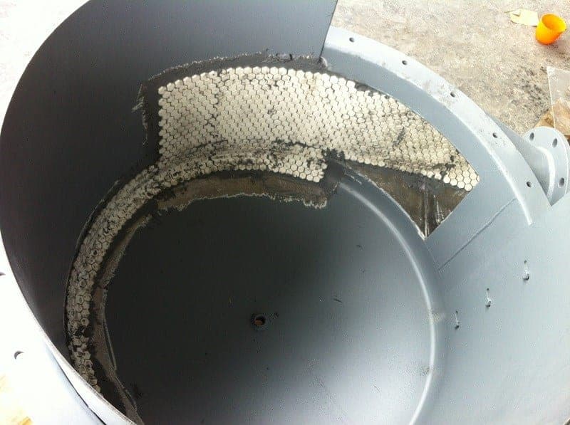 Interior of a gray fan or cyclone housing with a sheet of hexagonal ceramic tiles bonded into the wear path