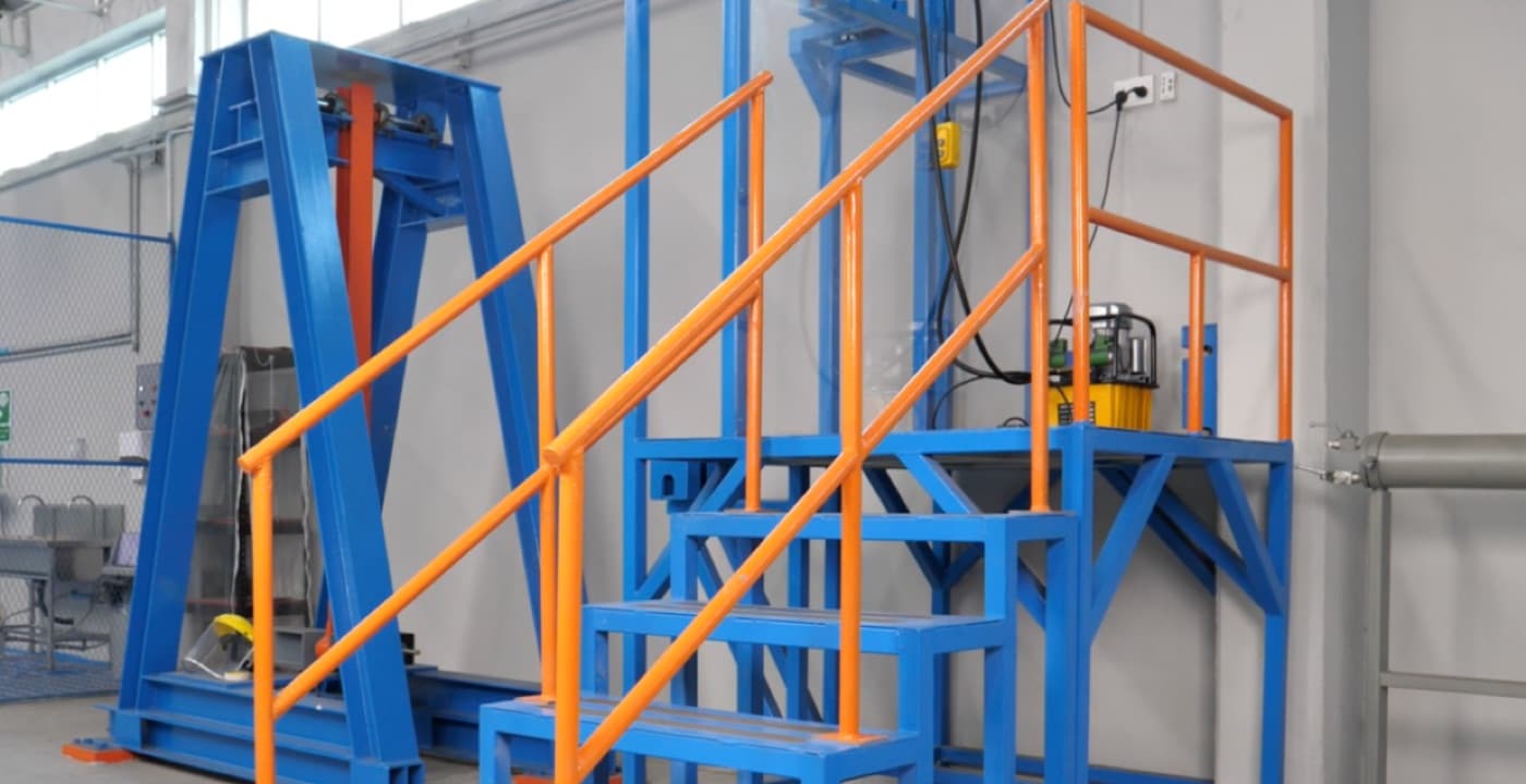 Blue steel access platform and stair with orange painted handrails, newly finished, inside a workshop
