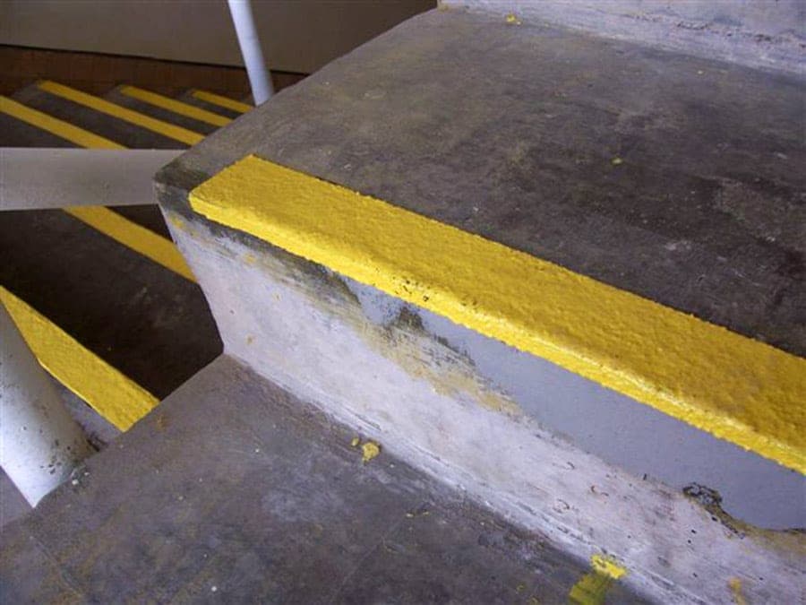 Concrete stair treads with bright yellow anti-slip nosings applied along each step edge